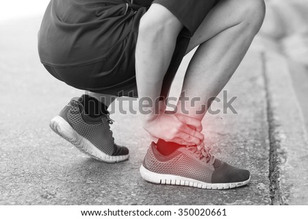 Runner touching painful twisted or broken ankle. Athlete runner training accident. Sport running ankle sprain.