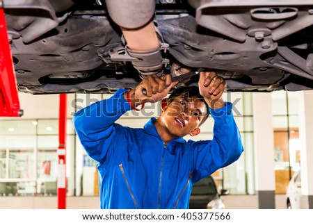 Mechanic standing and fixing under a lifted car with copy space