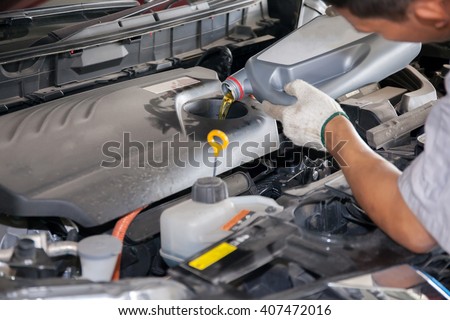 Servicing mechanic pouring new oil lubricant into the car engine