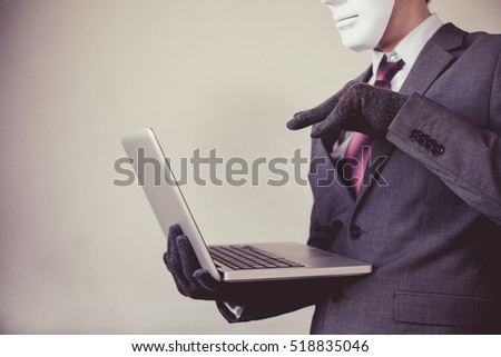 Business man in white mask wearing gloves and using computer - fraud, hacker, theft, cyber crime concept