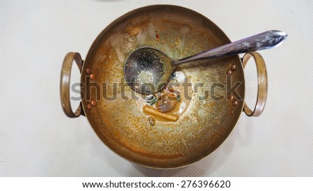 Dirty brass pan and dirt ladle after meal, brass pan can be versatile. Need to washing dirty brass pan. In this picture use it for serving hot spicy Tomyumkung (famous and delicious local thai food)
