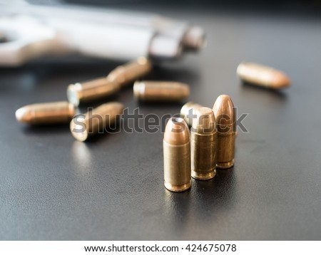 11mm bullets and short gun on black background. (selective focus)