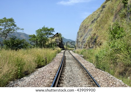 railway track running through middle of landscape with tunnel at the end