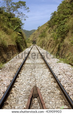 railway track running through middle of landscape with tunnel at the end