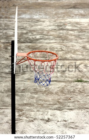 basket ball court on a rusty surface, contrasting colors against its surface pole and holder seen