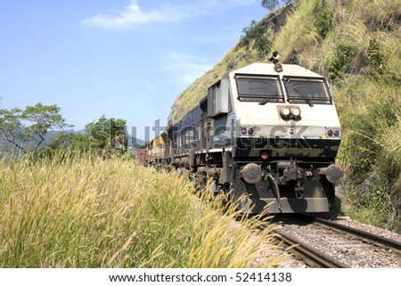 front view of the engine of a train passing by the middle of a landscape