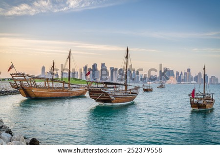 Dhows moored off Museum Park in central Doha, Qatar, Arabia, with some of the buildings from the city's commercial port in the background.