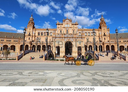 SEVILLE, SPAIN - MARCH 26 2014: Tourists ride a horse-drawn carriage in front of the Plaza de Espana in Seville, Spain. The Plaza is a major tourist destination that was built in 1928.