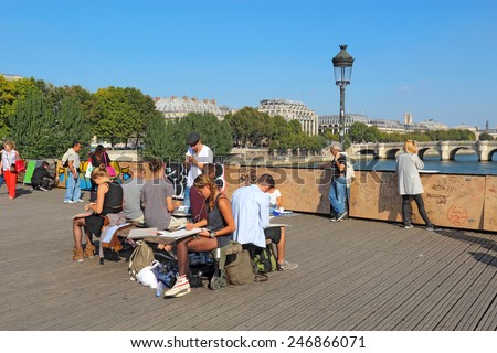 PARIS, FRANCE - SEPTEMBER 10 2014: Students doing plein air sketches on the Pont des Artes. This pedestrian bridge over the Seine is very popular with students, artists, photographers and lovers.
