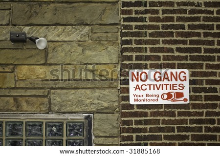 No gang activities sign against red brick and stone walls with security light