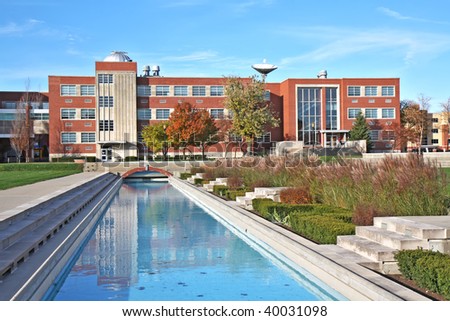 Lilly Science Hall and reflecting pool on the campus of the University of Indianapolis in Indiana with landscaping of the Smith Mall against a background of blue sky and white clouds