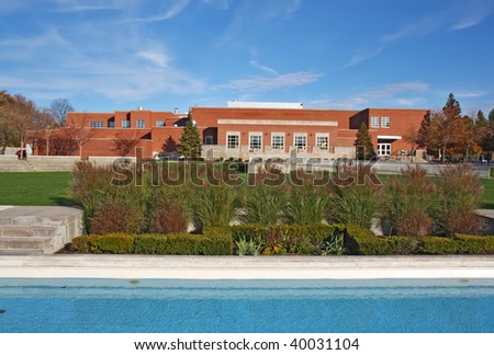 Schwitzer Student Center on the campus of the University of Indianapolis in Indiana with landscaping and reflecting pool of the Smith Mall against a background of blue sky and white clouds