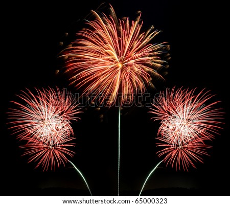 Three bursts of red white and gold fireworks against a black night background