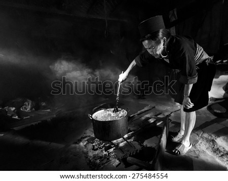 SAPA, VIETNAM - MARCH 18: Unidentified minority tribe of a elderly woman cooking corn food for the domestic animals inside her home on March 18, 2015 of Sapa, Vietnam.