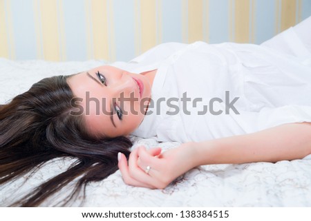 Attractive brunette on the bed with white bed linen.