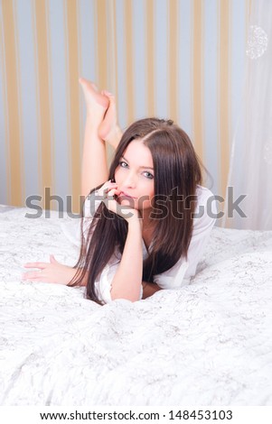 Attractive brunette on the bed with white bed linen.