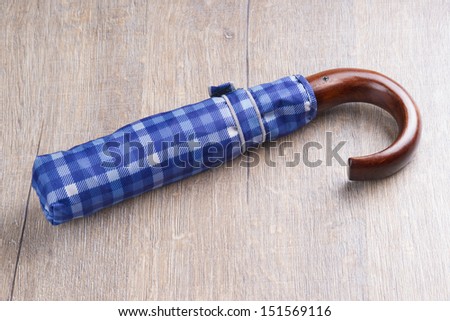 Folded blue umbrella on wooden table