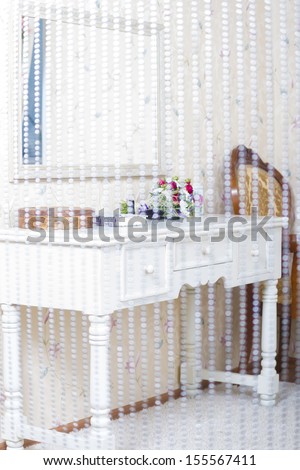 Makeup table with mirror in a bedroom shot through curtains