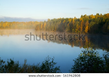Light fog above calm lake in sunny autumn morning, Karelia, Russia