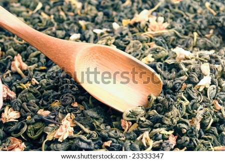 Authentic bamboo spoon in dried green tea leaves with jasmine flowers. Green tea is a traditional chinese drink