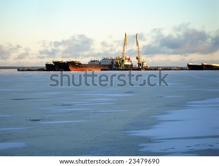 Cranes in dockside before the sunset on a frozen lake - industrial landscape