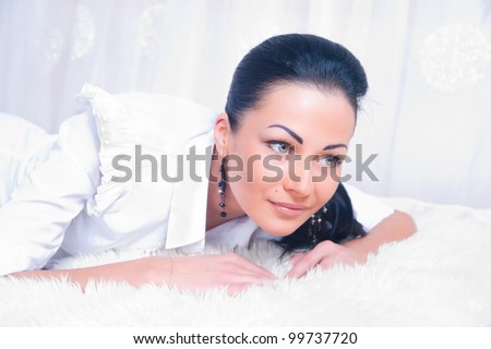 Portrait of brunette woman on the bed with white bed linen.