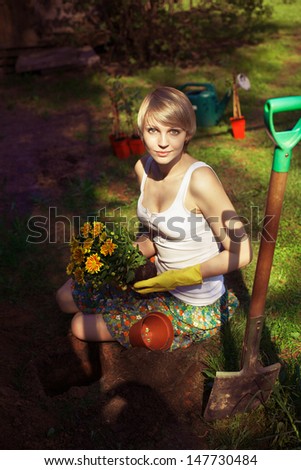 Happy young woman gardening with spade in garden