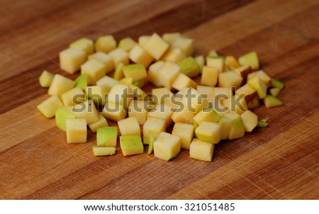 A pile of diced golden delicious on a cutting board.