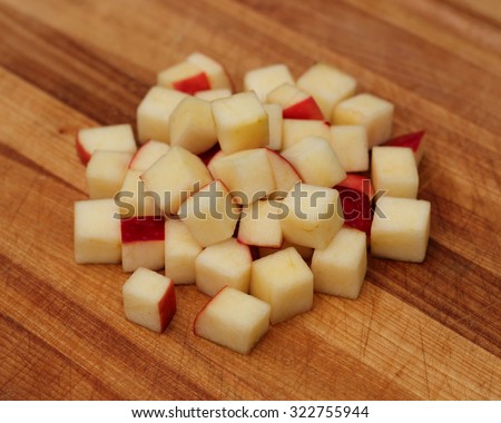 Symmetrically diced red apple sitting by itself on a wooden background.