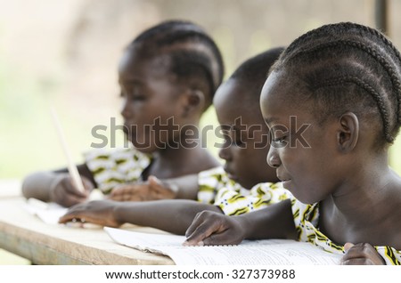 Two beautiful African girls and one African boy reading and writing at school as an educational symbol outside their school in Bamako, Mali. Beautiful education symbol background.
