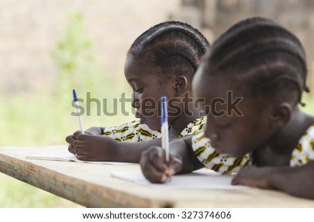 African Children at School Doing Homework. African ethnicity students writing their essay in an African school. They\'re holding blue pens to write down their homework whilst sitting in their desk.