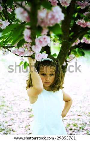 Cute girl posing under a japanese cherry-blossom tree. Cross-processed