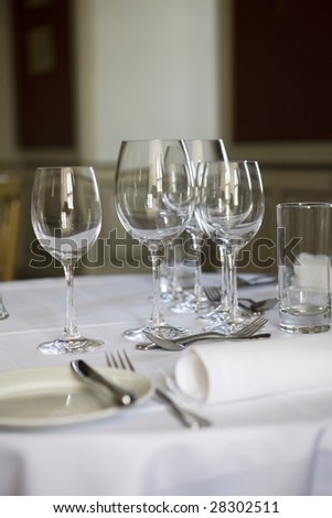 Dining table with wine glasses and white tablecloth ready for guests