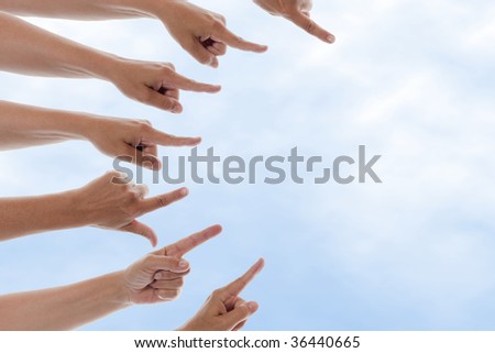 Many hands pointing to the right with a blue sky in the background