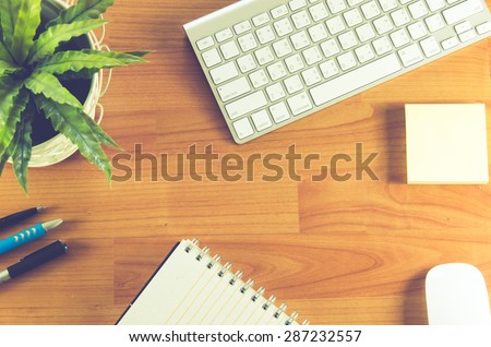 Business desk with smart phone ,  mouse and keyboard on wooden table.vintage style effect picture