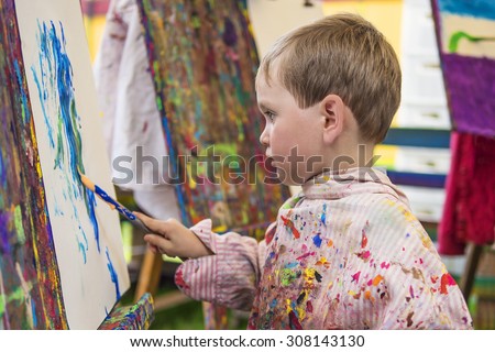 Cute little preschooler making a painting in art class
