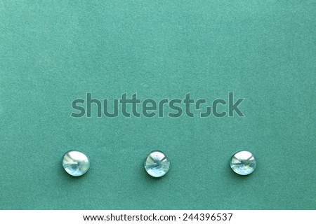 Turquoise rough paper background with three smooth glass pebbles