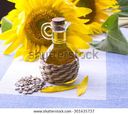 Decanter with sunflower oil. Flowers with a bottle of sunflower oil. Small bottle with sunflower oil and purified seeds.