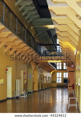 Looking up a deserted aisle lined on both sides with three levels of prison cells.