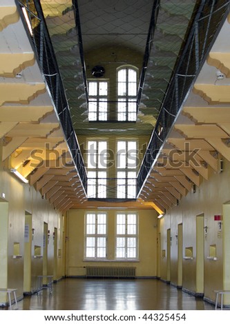 Looking down a deserted aisle lined on both sides with three levels of prison cells.