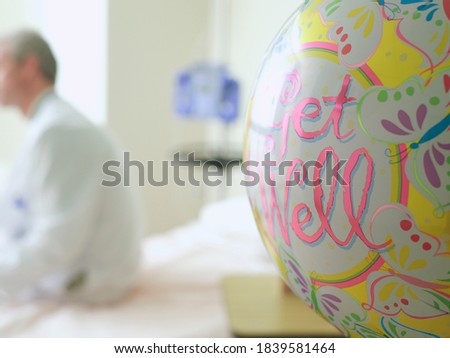 Close-up shot of a \'Get Well\' balloon in hospital with doctor in background and copy space.