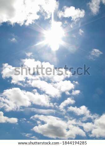 The sun shines bright in the daytime in summer with fluffy clouds in the blue sky.