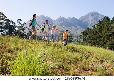 Horizontal profile shot of a couple with their two children walking in a line on a hike on a mountain trail with copy space.