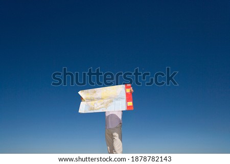 A man looking at the map on the highway on a bright sunny day with a clear sky in the background.