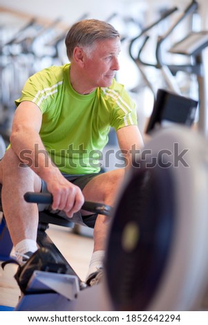 A senior man in gym taking a break and resting on a rowing machine after a continuous session of workout