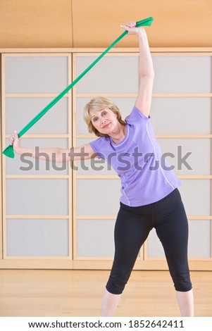 A vertical portrait of a fit senior adult woman using resistance band in a gym for stretching and exercising