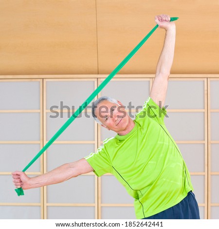 A portrait of a senior-adult man exercising with resistance band in a gym to stay fit