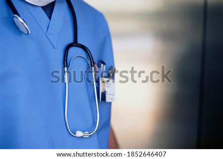 A cropped closeup shot of a doctor in a scrub suit with a stethoscope hanging from the shoulder