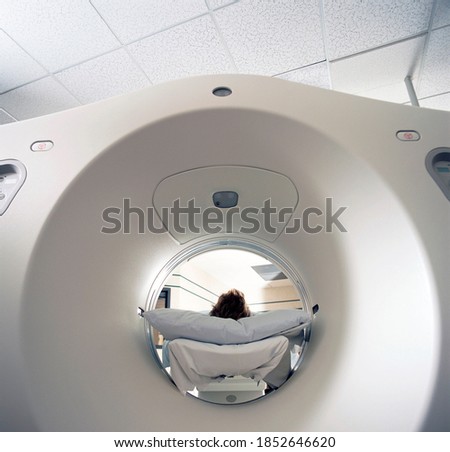 A frontal view of an advanced MRI scanning machine with a patient entering in for getting scanned