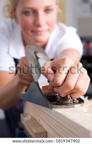 A close up portrait shot of a young girl\'s hands planning wood in a vocational school.